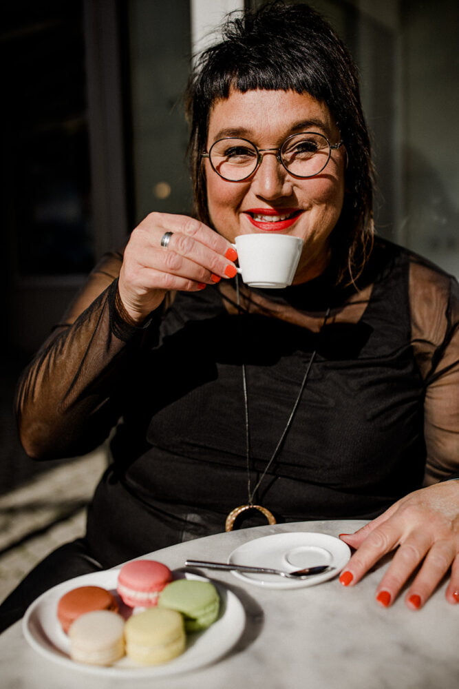 Autoren-Foto von Sabine Jung-Baß, die in die Kamera schaut mit einer Tasse Kaffee